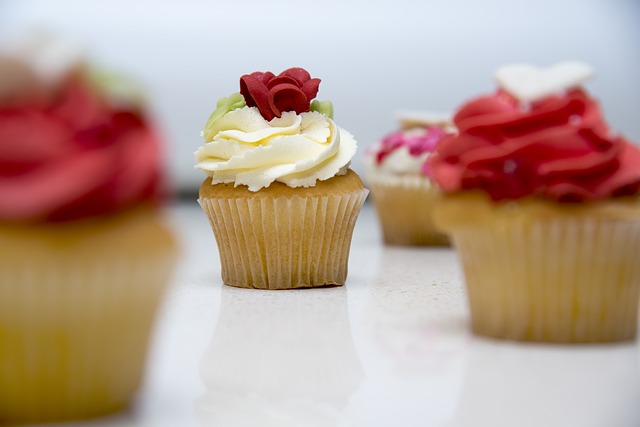 vanilla cupcake topped with white buttercream frosting and a red frosting rose