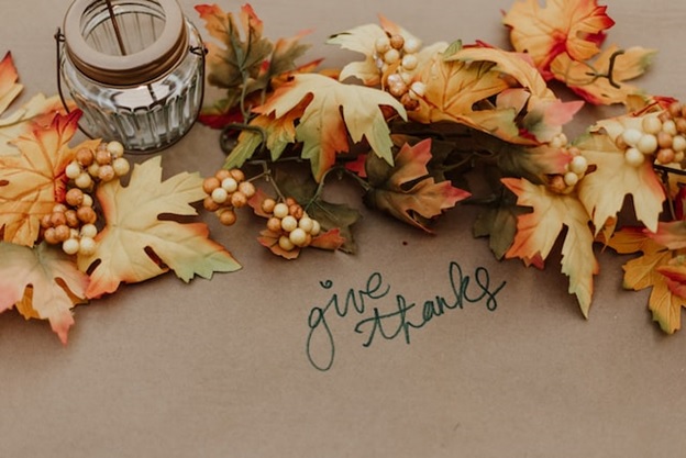 thanksgiving table decorations on a kraft paper tablecloth with the words "give thanks" in green ink